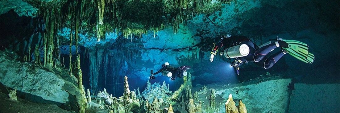 Divers explore a cenote cavern.