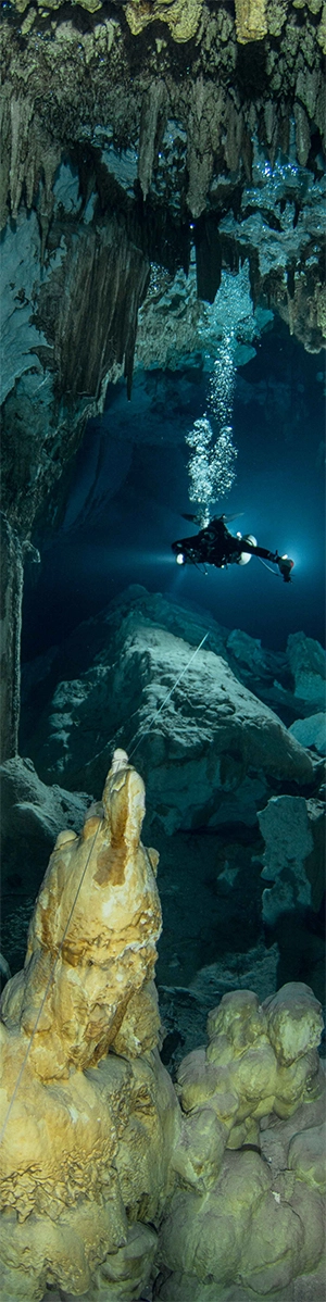 Diver shines a torch into cavern depths