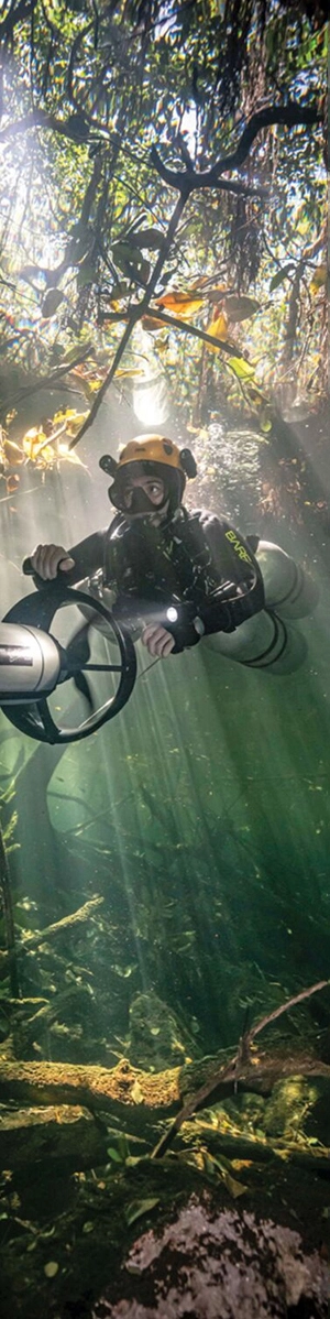 Diver uses underwater propulsion vehicle to explore a cenote