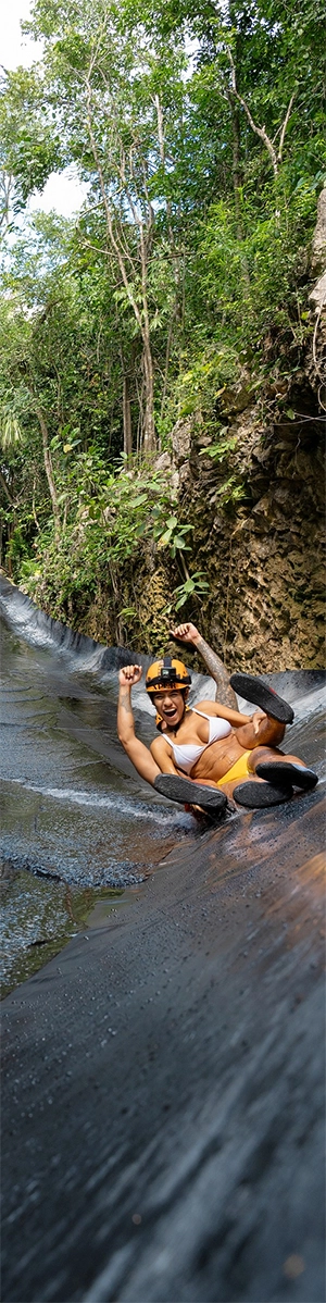 A couple speed down a water slide at Xplor in the Riviera Maya