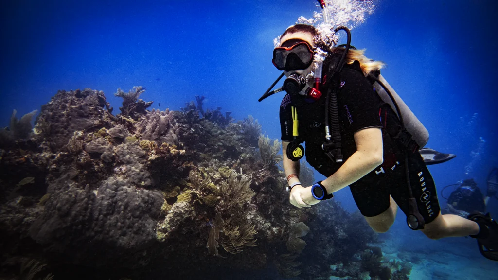 Young girl scuba dives at Manchones Grande Reef