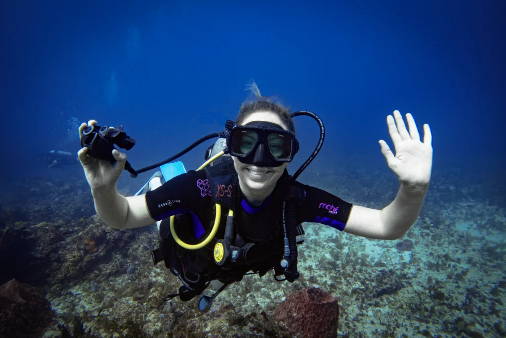 Diver removing her regulator and smiling underwater