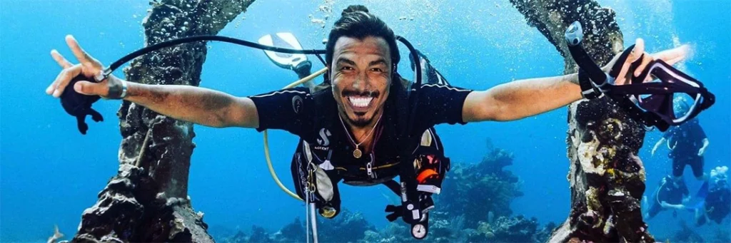 Instructor Juan smiles while swimming through an underwater sculpture named Seascape