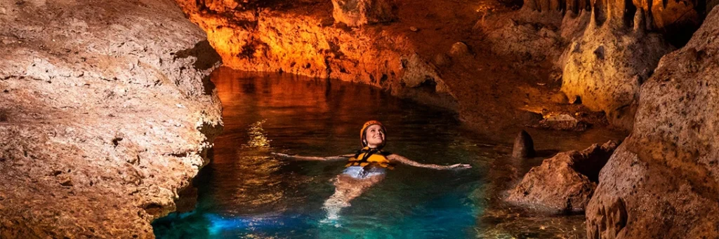 Woman smiles as she floats down an underground river